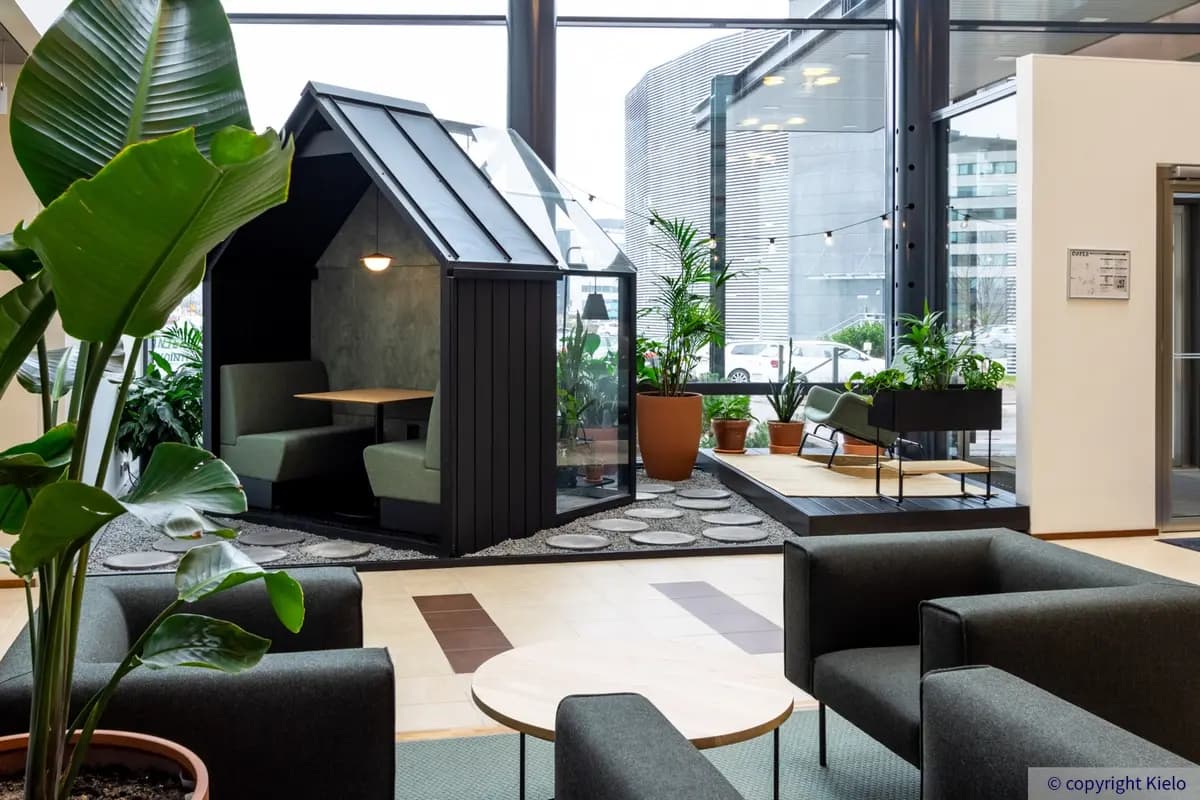 Gate8 Business Park Largo-talon aulassa on paljon viherkasveja, nojatuoleja sekä talon muotoinen loosi.