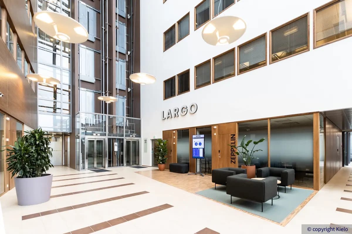 Gate8 Business Park Largon avara ja korkea hissiaula. Lasihissien edessä on muutamia nojatuoleja.