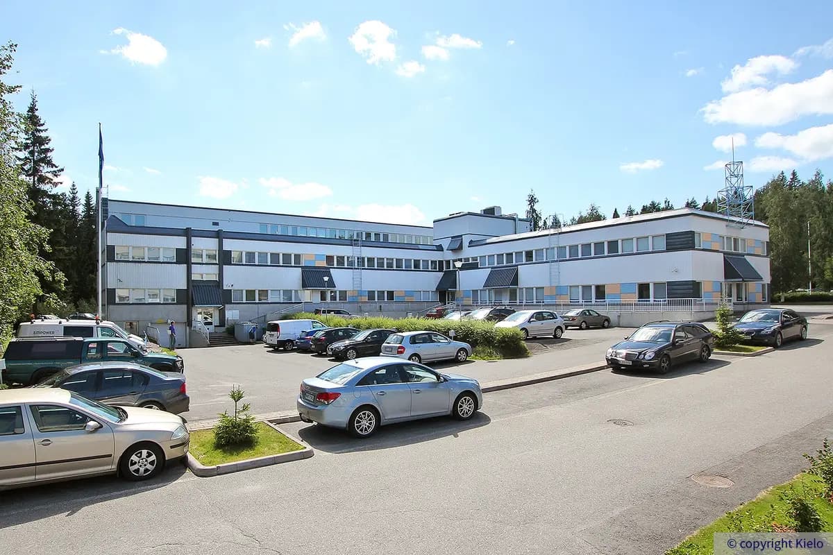 Jyväskylän Ylistönmäentie 24, kiinteistöstä kesällä otettu ulkokuva, jossa näkyy rakennuksen parkkipaikka.