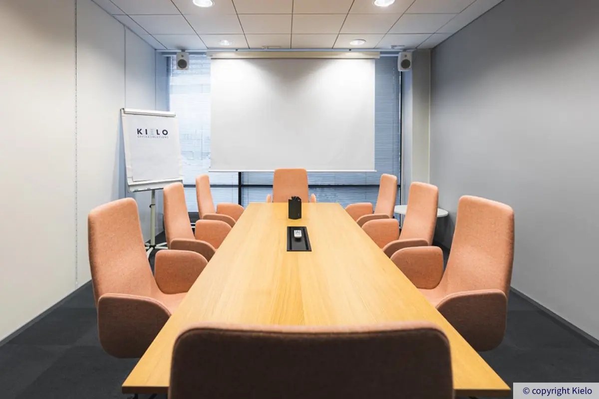 Innova 2 neuvotteluhuone. kuvassa iso ruskea pöytä jonka ympärillä tuoleja, pöydän takan iso ikkuna sekä fläppitaulu.