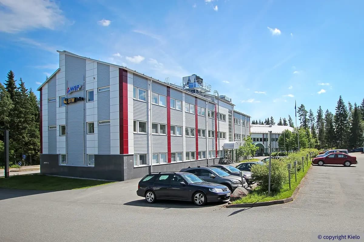 Toimitilakiinteistö Jyväskylän Ylistönmäentie 31 kuvattuna rakennuksen luoteiskulmasta sisäpihanpuolelta. Talon edessä pysäköityjä autoja.