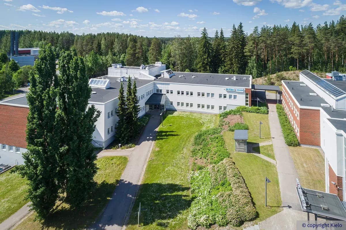 Lappeenrannan Laserkatu 6 rakennus C ilmakuvattuna. 2-kerrosisessa toimitilarakennuksessa on valkea julkisivu ja tasakatto. Talon edessä vihreä nurmikenttä.