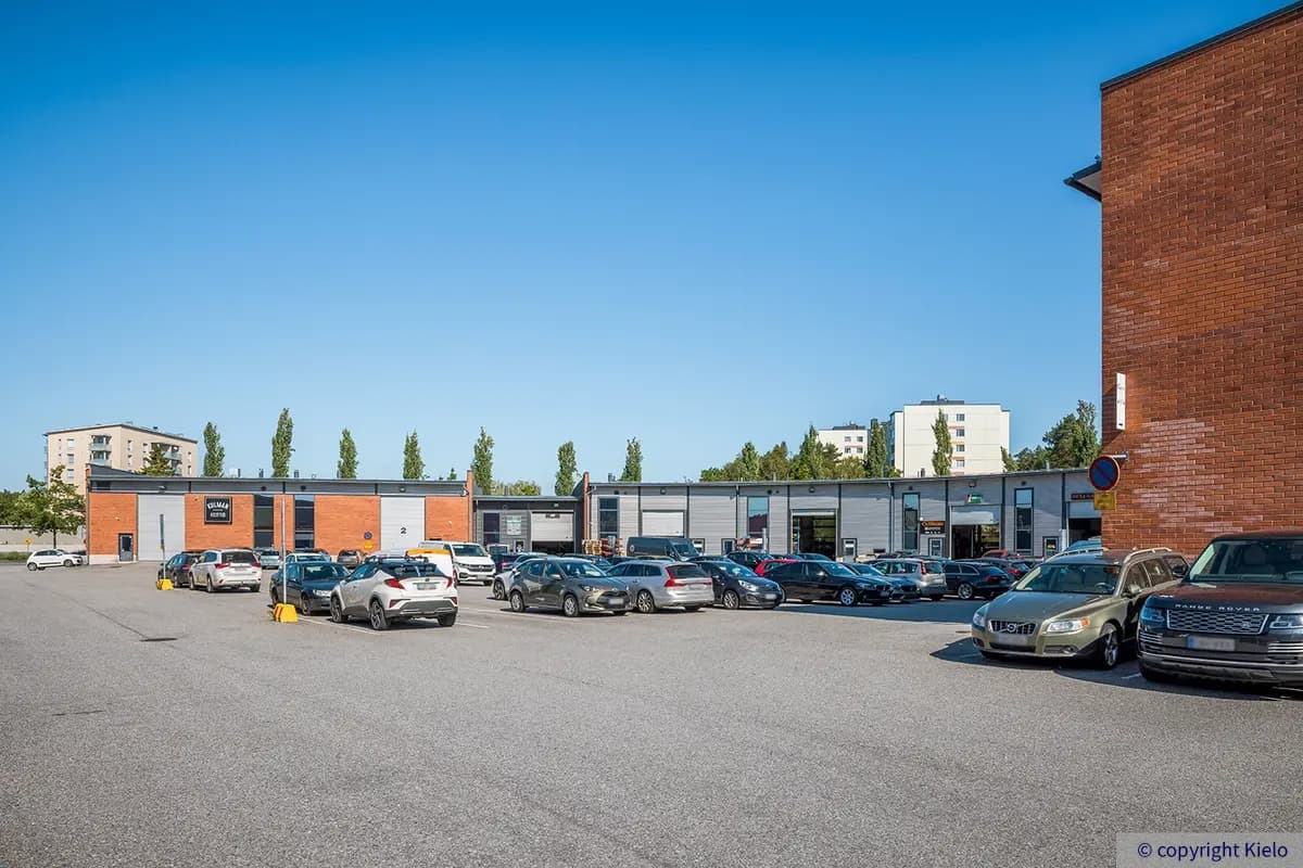 Purocenter sisäpihan asfaltoitu pysäköintialue. Kaarevassa rakennusosassa on nosto-ovellisia tiloja.