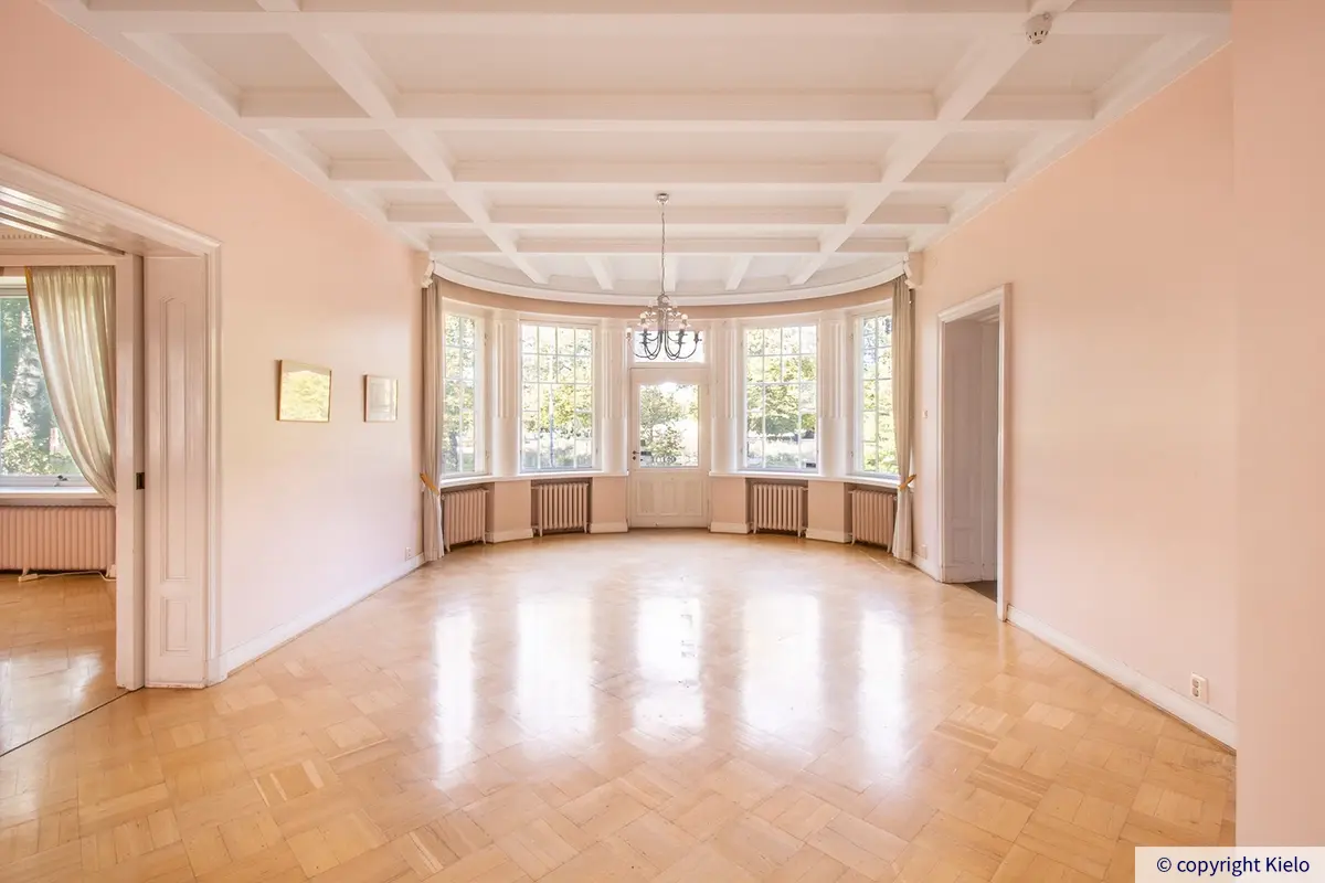 36Hatanpään Konsulitalon valoisa avotila, jossa suurilla ikkunoilla ja ovella varustettu erkkeri.