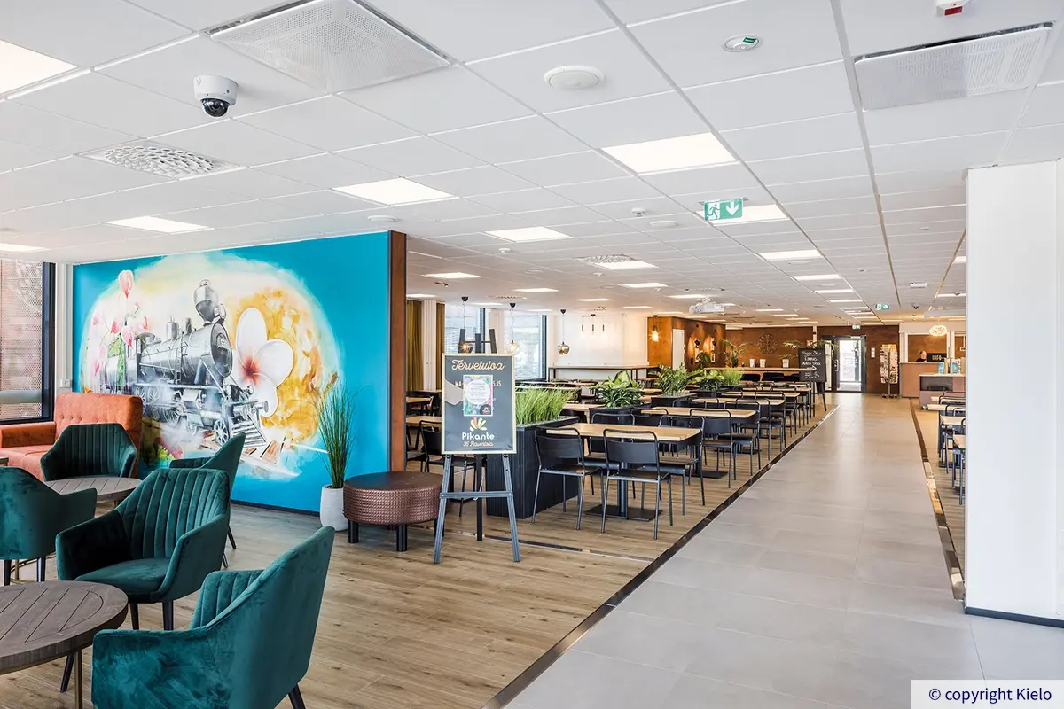 Viihtyisä ravintola Pikante 36Hatanpäässä. Ravintolasalissa on värikäs seinämaalaus höyryveturista. Ruokapöytäryhmien lisäksi on tummanvihreitä nojatuoliryhmiä.