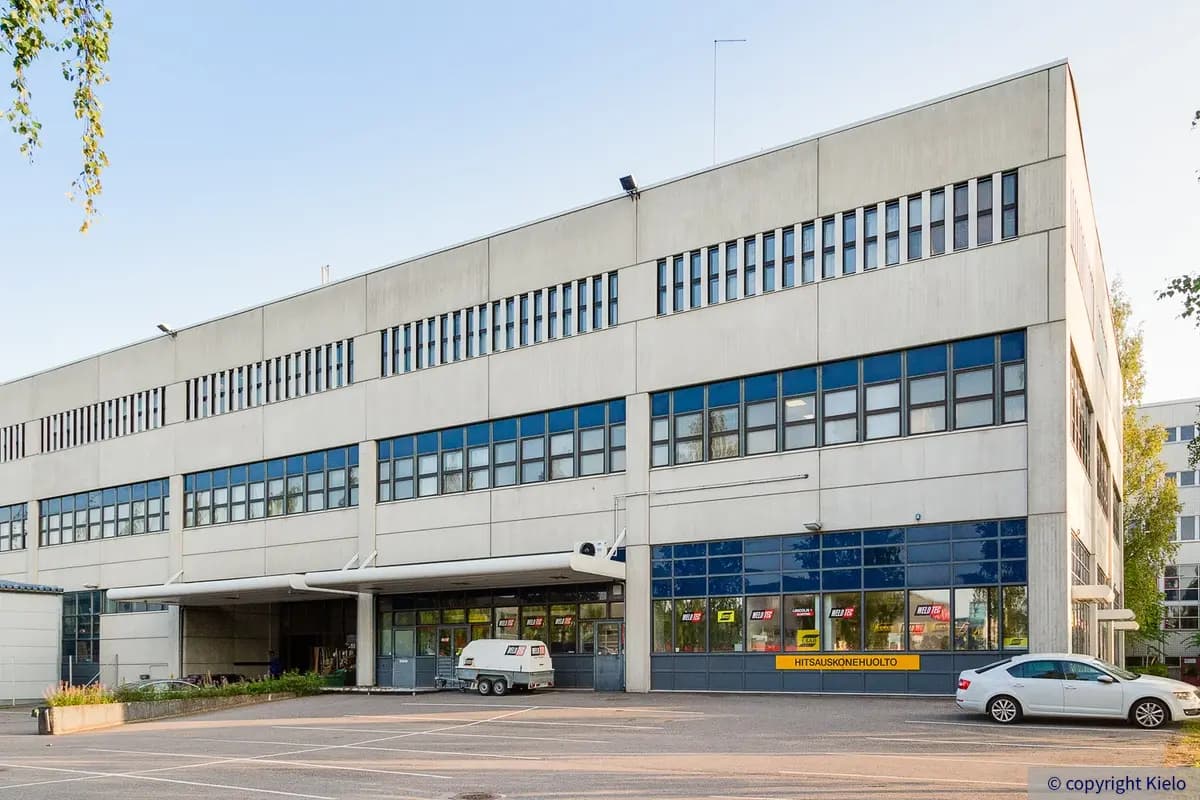 Helsingin Laippatie 1, ulkokuva. Vaalea rakennus jossa siniset ikkunakarmit. Talon edustalla pysäköintialue.