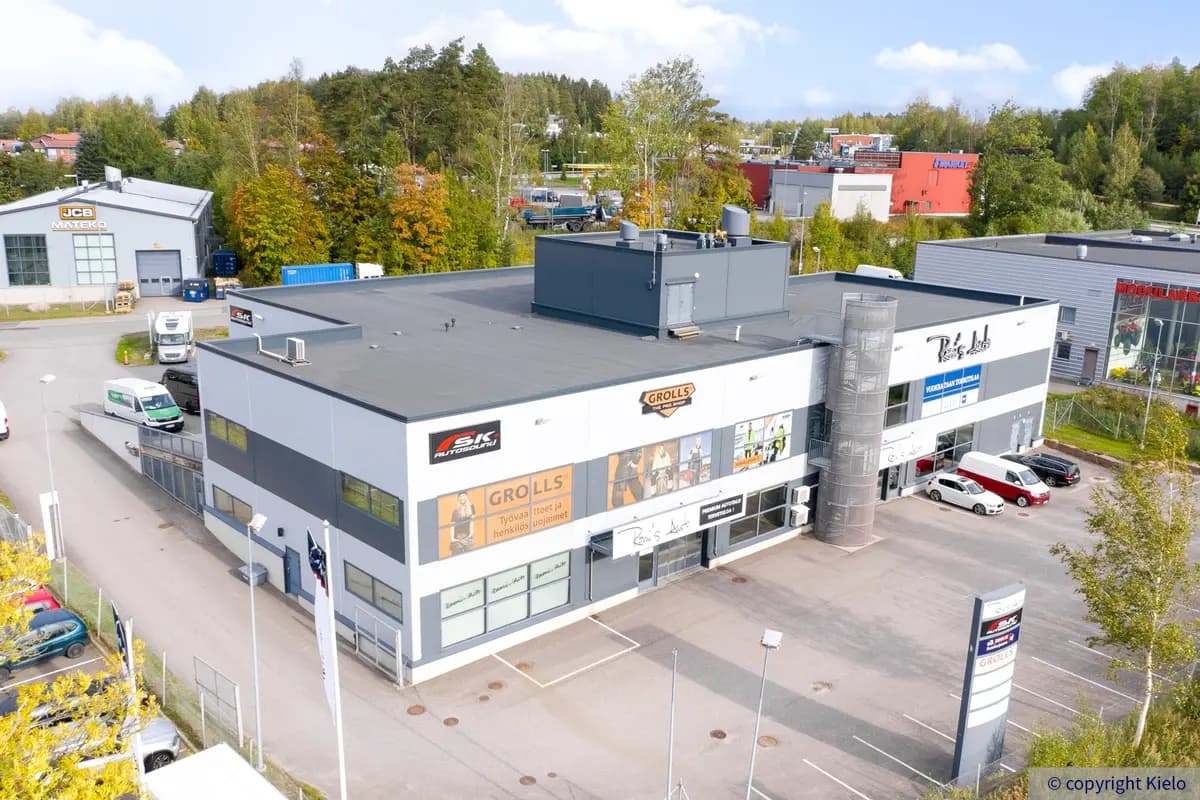 Espoon Kartanonherrantie 7, ilmakuva. Kuvassa rinteessä oleva, kaksikerroksinen rakennus, ympärillä asfaltoitua pihaa jossa autoja pysäköitynä. Taustalla muita rakennuksia ja metsikköä.