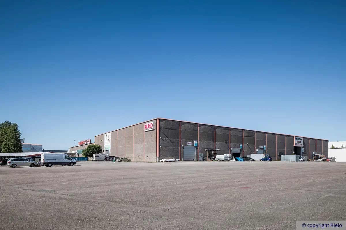Tampereen Yrittäjänkulma 5 harmaa teollisuushalli, jossa seinustalla suuret nosto-ovet. Iso ja tasainen piha-alue on asfaltoitu.