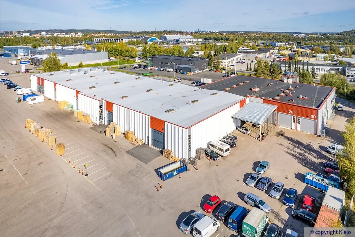 Tampereen Nuutisarankatu 15 ilmakuvassa suuren asfaltoidun pihan puolelta. Rakennuksessa useita nosto-ovia.