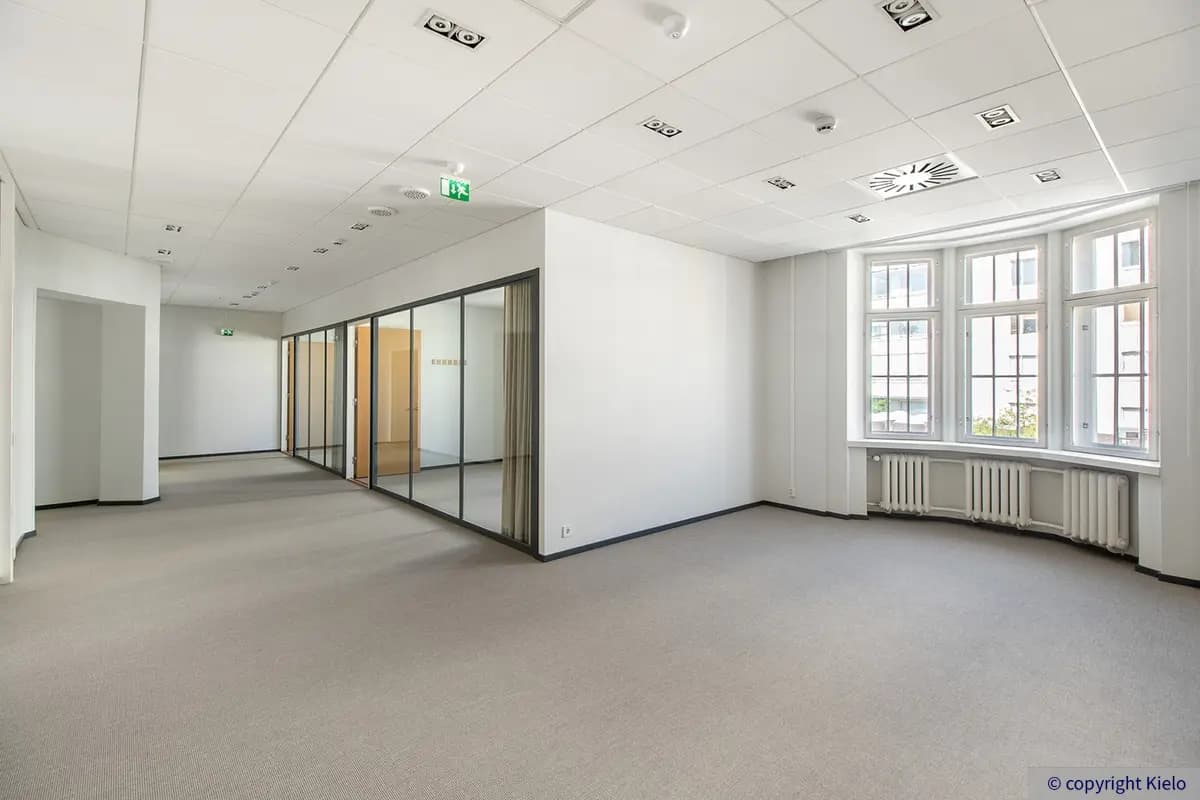 Puistonkulma valoisa toimistotila, jossa avotilaa ja lasiseinien takana neuvottelutilat.