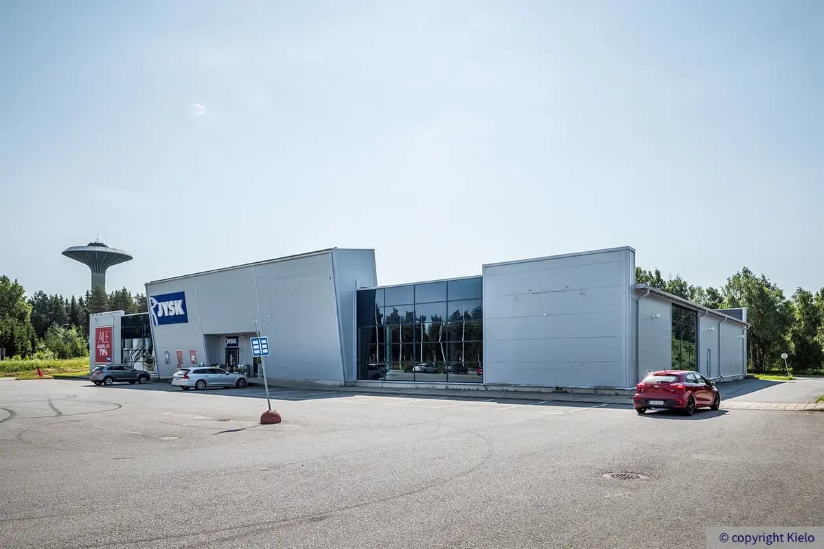 Raahen Jokelantie 5 vaaleanharmaa julkisivu, jossa peililasiset osat. Edessä pysäköintialue, taustalla vesitorni.