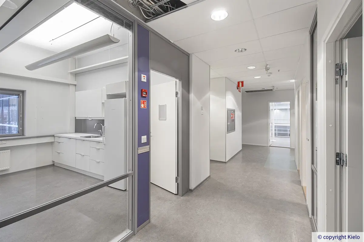 Jyväskylän Mattilanniemi 6-8 471 m2 toimistotilan käytävä, jossa lasiseinän takana valkea keittiö.