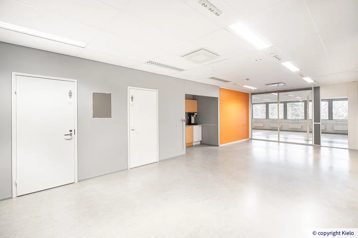 Jyväskylän Ohjelmakaari 10 viidennen kerroksen 695 m2 toimitilan avotila, jonka laidalla ovet vessoihin sekä keittiökalusteet.