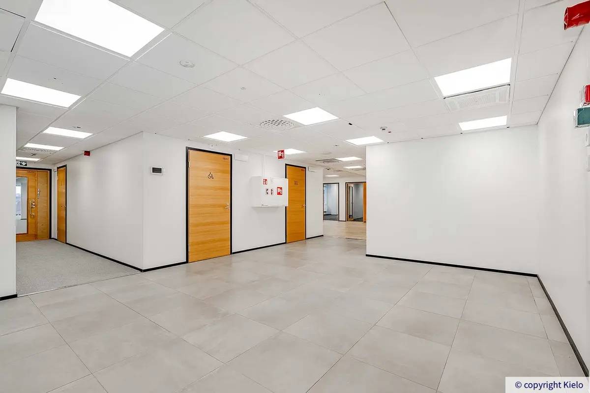 Toimistotilan sisäänkäynti ja käytävää. Ovet vessoihin, joista yksi on esteetön.