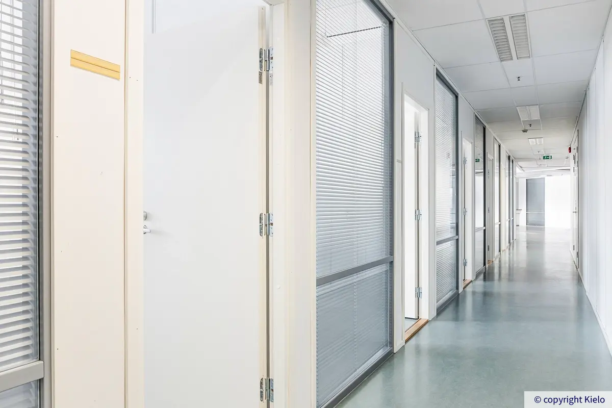 Jyväskylän Mattilanniemi 6-8 toimitilan 3Ba1 käytävä. Vihertävä muovimatto, toimistohuoneita rivissä.