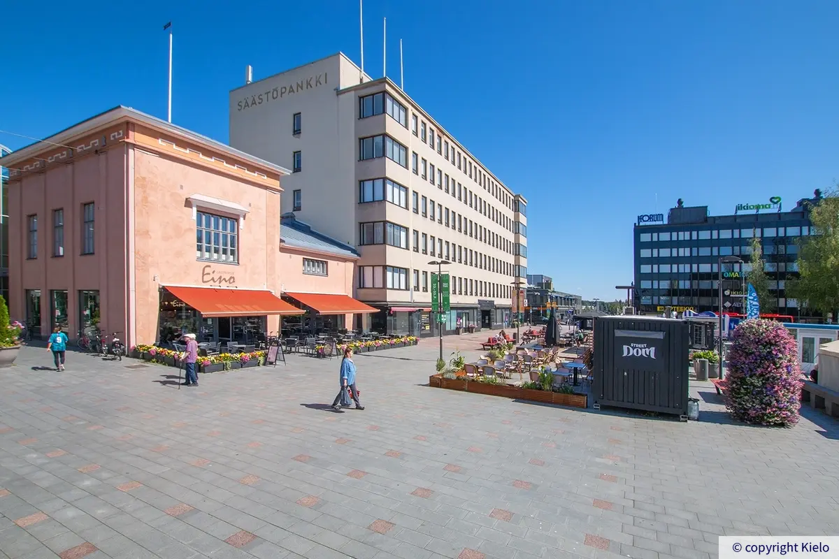 Toimitilakiinteistö Hallitustorin laidalla. Talon edustalla torialue, jolla on kävelykatu ja terasseja.