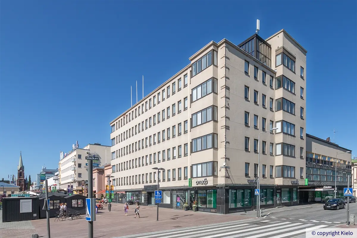 Vaalea kuusikerroksinen toimitilakiinteistö Hallitustorin laidalla.