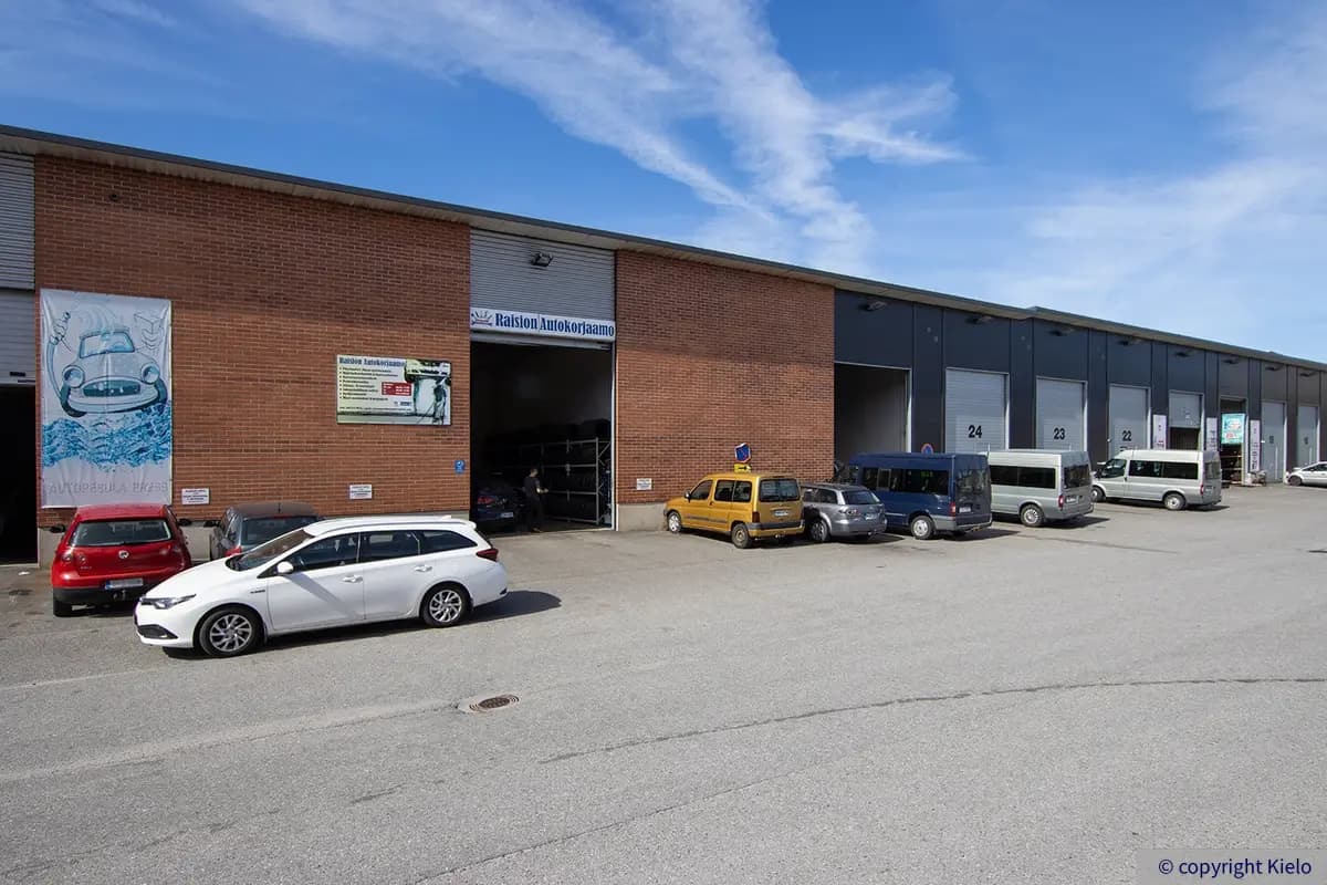 Purocenter sisäpihalle aukeavia nosto-ovellisia varastotiloja, joiden edessä pysäköitynä autoja. Varastotiloissa mm. autopesula ja autokorjaamo.