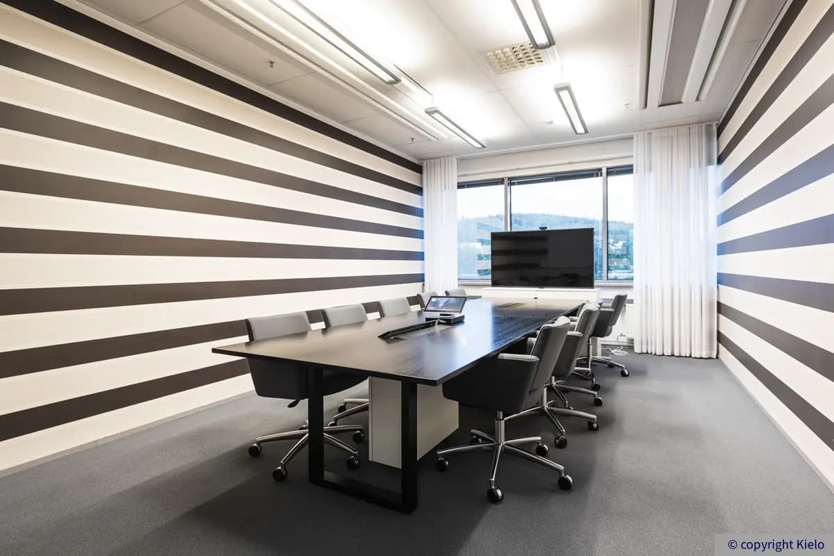Jyväskylän Mattilanniemi 6-8 sijaitsevan toimitilakiinteistön 1. kerroksen 1260 m2 toimiston neuvotteluhuone, jossa tumma neuvottelupöytä. Pöydän päädyssä televisio ja isot ikkunat.