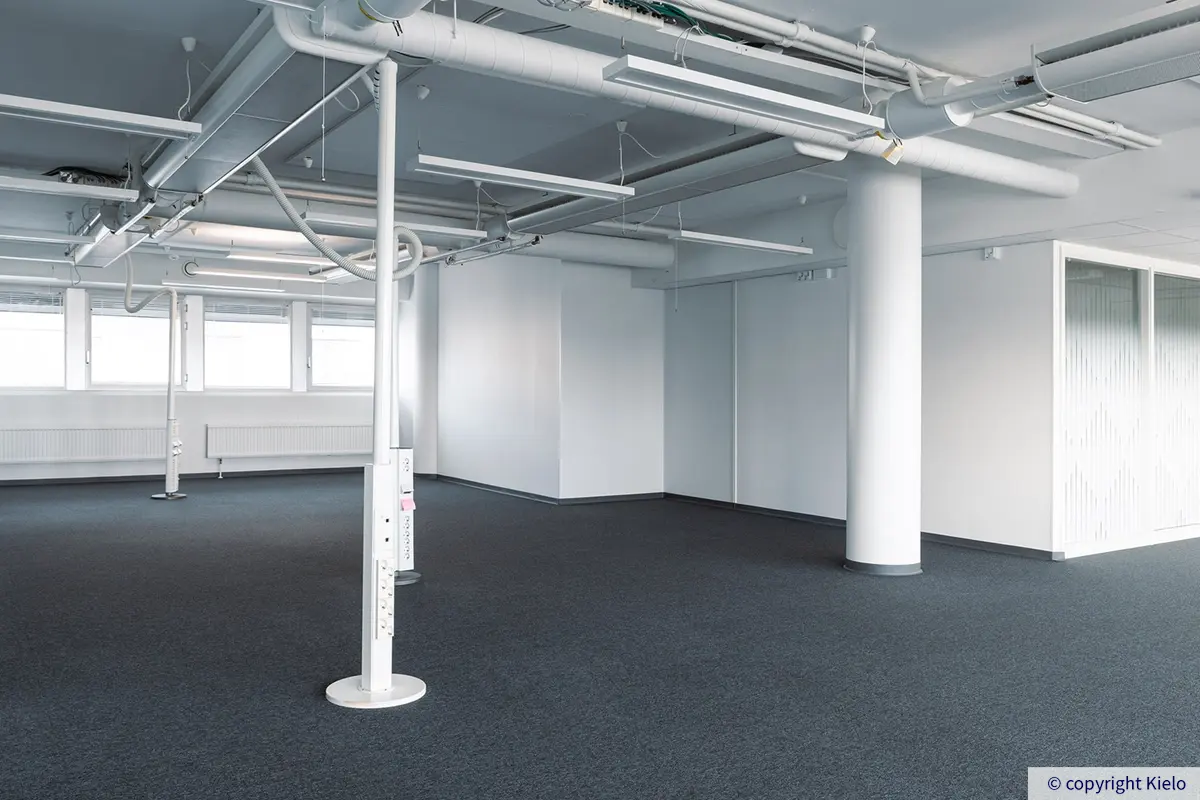 Jyväskylän Vapaudenkatu 48-50 toimitilakiinteistössä sijaitsevan toimiston avotila, jossa tumma kokolattiamatto.