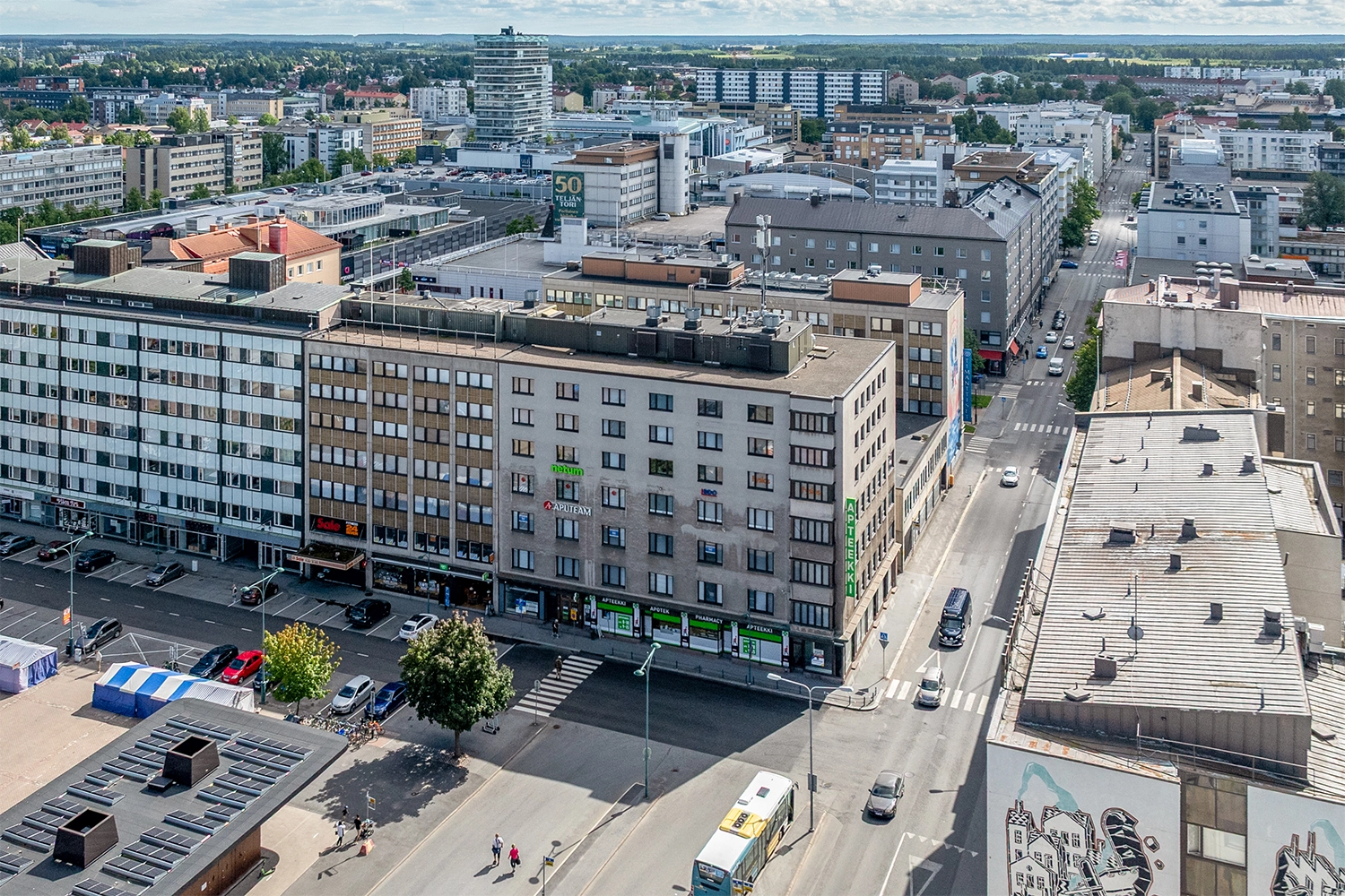 Monikerroksinen liikerakennus, jossa on Apteekki-kyltti. Kiinteistö sijaitsee katujen risteyksessä, kauppatorin kulmalla.
