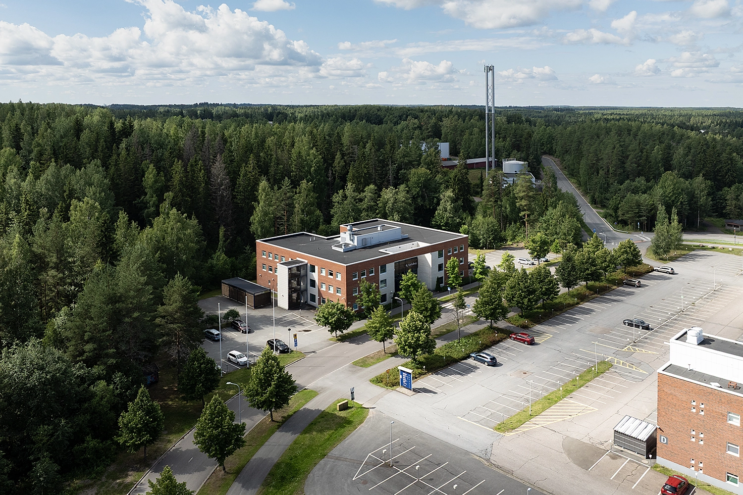 Kielo Lappeenranta – Teknologiapuistonkatu 10 punatiilinen toimitilakiinteistö puiden lomassa.