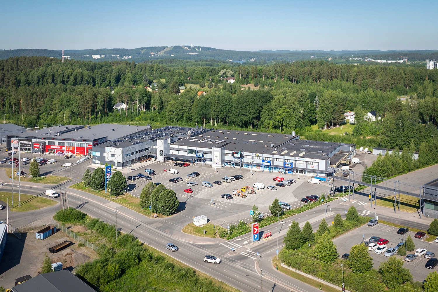 Jyväskylän Vasarakatu 27 on iso, L-muotoinen toimitilakiinteistö, jonka edustalla on asiakaspysäköintialue. Taustalla ilmakuvassa näkyy Laajavuori.