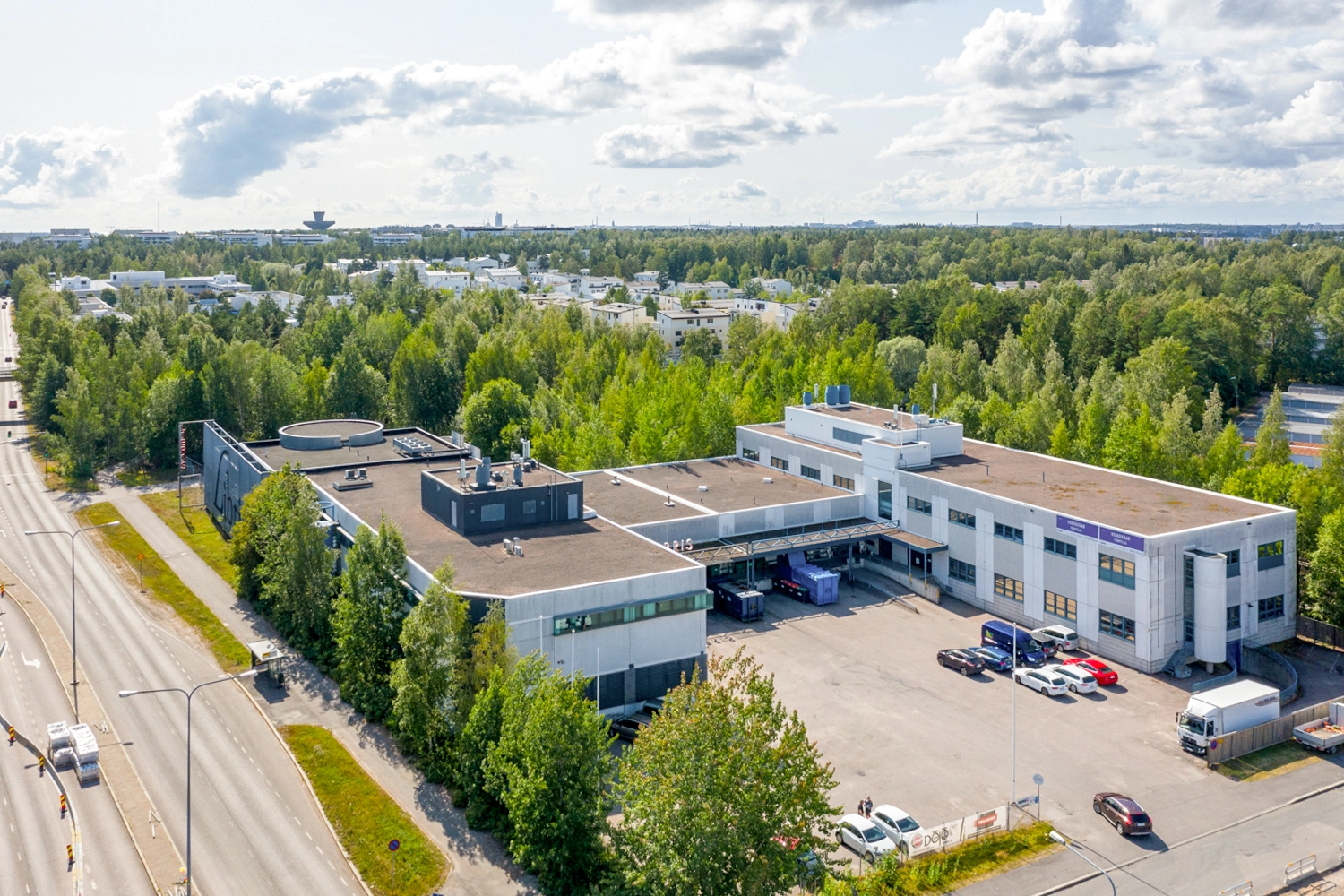 Helsingin Lirokuja 4 ilmakuvassa. Vaalea betoninen pienteollisuuskiinteistö, jonka pihassa pysäköityjä autoja.