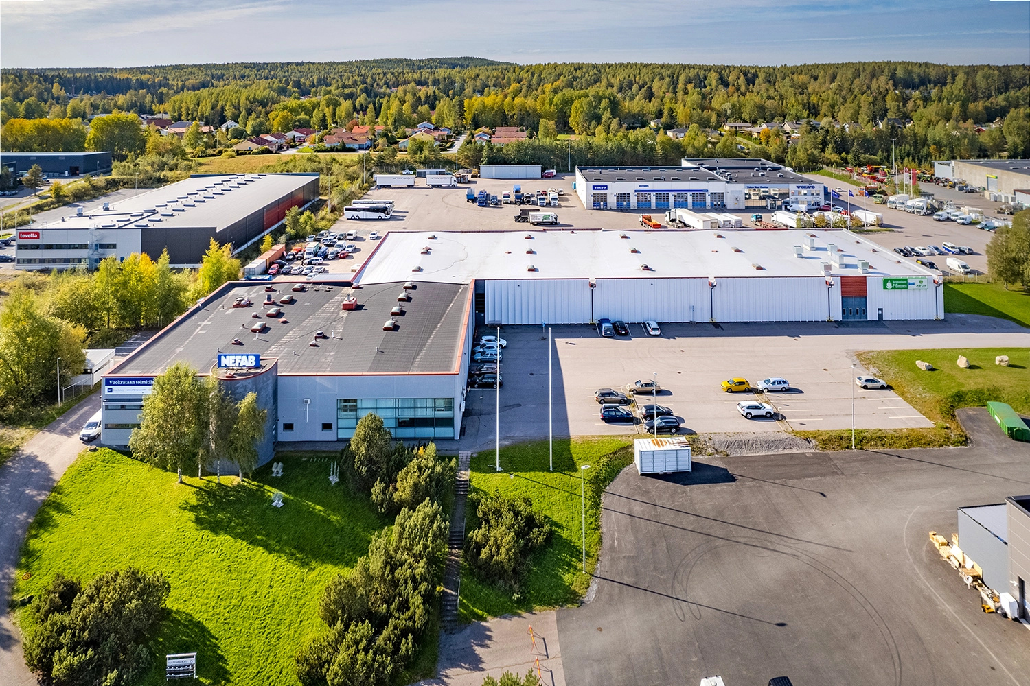 Suuri kahdesta laatikkomaisesta rakennuksesta koostuva Tampereen Nuutisarankatu 15 ilmakuvassa pysäköintialueiden ympäröimänä.