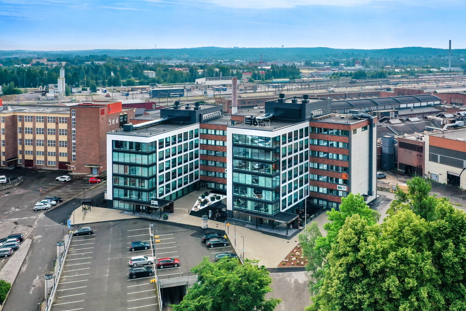 Remontoitu, pääosin punatiilinen toimistokiinteistö 36Hatanpää ilmakuvassa. Edessä pysäköintitilaa, takana ratapiha.